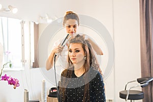 Working day inside the beauty salon. Hairdresser makes hair styling photo