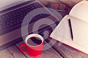 Working desk with cup of coffee planner agenda laptop and mobile phone vintage morning