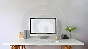 Working desk is surrounding by a white blank computer monitor and office equipment.