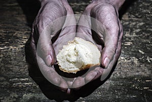 Working dirty hands of a man holding a crust of bread. Begging for a hand of hope. Give hope. The concept of alms and charity
