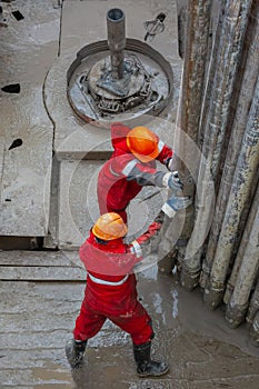 A working driller installs a drill pipe raised from a well.