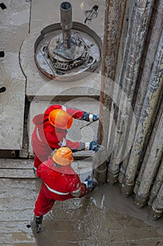 A working driller installs a drill pipe raised from a well.