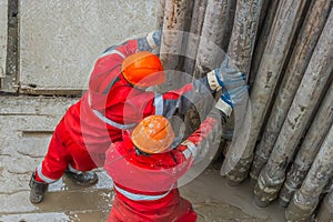A working driller installs a drill pipe raised from a well.