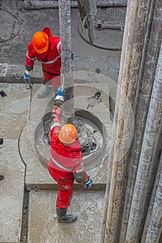 A working driller installs a drill pipe raised from a well.