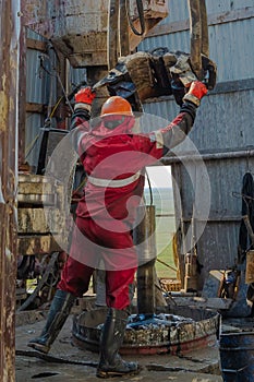 A working driller lifts drill pipes from a well.