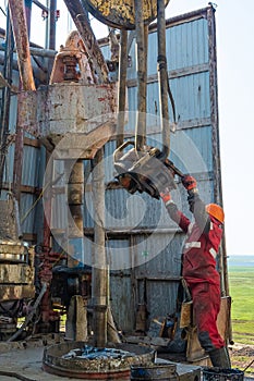 A working driller lifts drill pipes from a well.