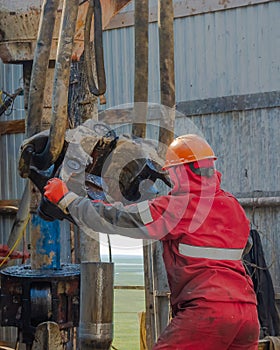 A working driller lifts drill pipes from a well.