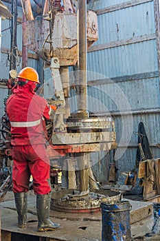 A working driller is screwing drill pipes to run into the well.