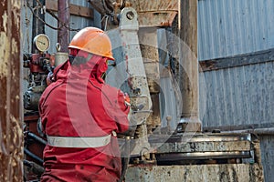 A working driller is screwing drill pipes to run into the well.