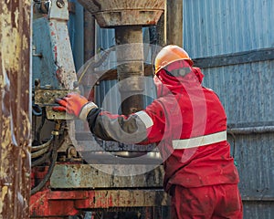 A working driller is screwing drill pipes to run into the well.