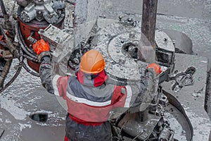 A working driller is screwing drill pipes to run into the well.