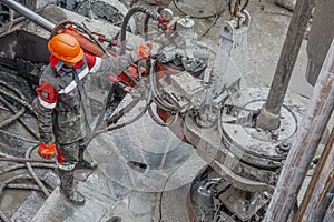 A working driller is screwing drill pipes to run into the well.