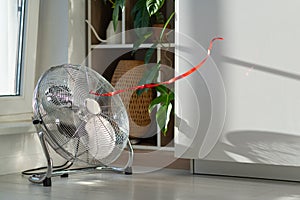 Electric fan with red wriggle ribbon designed to cool air and supply wind located near window photo