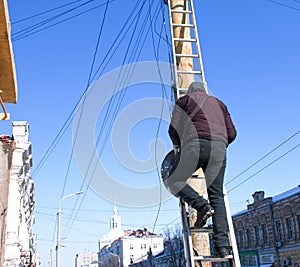 A working electrician repairs an electrical line at a high altitude