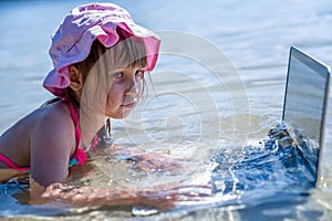 Working always and everywhere. Funny and humorous image of little cute girl freelancer working with laptop outdoors in tropical