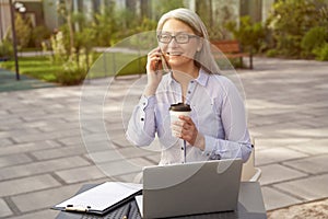 Working from everywhere. Portrait of a happy beautiful mature business woman drinking coffee and talking with on mobile