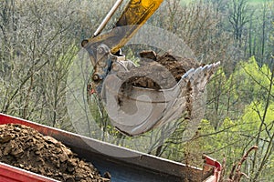 Working excavator shovel. Dump truck detail with soil pile. Building machine