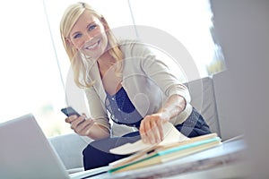 Working through the files. Portrait of a happy businesswoman sending a text message while sitting in her office.