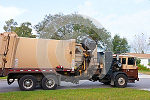 Working garbage truck with robotic arm dumping can of trash into onboard compactor