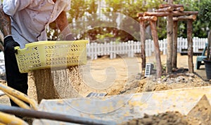 Working with garden tools, shovel and wheelbarrow with pile of sand on the site of a country house