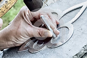 Working with hammer during hand stamping or engraving decoration pattern on metal ornament
