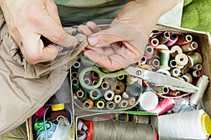 Working hands of a seamstress with a needle, scissors thread