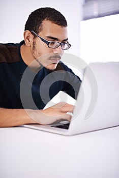 Working hard on a brand new design. a handsome young man working on his laptop in an office.