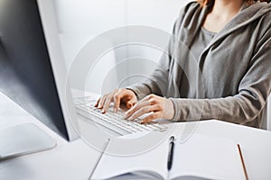 Working hard to party weekends. Cropped shot of woman typing on keyboard, sitting in front of computer monitor