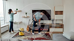 Working hard. Two professional cleaners in uniform working together in the living room. Young caucasian man cleaning the