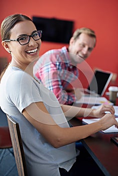 Working here is a blast. Cropped portrait of two young colleagues sitting in a boardroom.