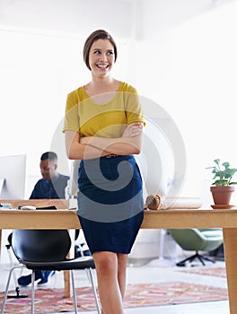 Working herself up in the company. A young woman in the office with colleagues in the background.