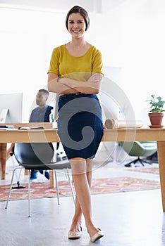 Working herself up in the company. A young woman in the office with colleagues in the background.