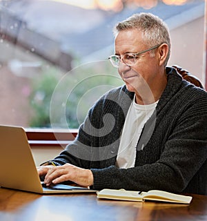 Working on his retirement plan. a handsome senior man working on his laptop in the study.