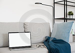 Working from home, laptop computer with blank empty white screen display monitor on sofa. Mock up, copy space.