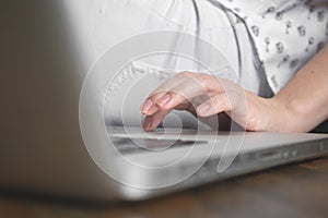 Working from home with laptop computer. Woman hand typing on keyboard sitting on floor at home. Freelancer concept