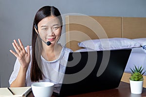 Working from home, new normal concept. attractive happy woman with headset making video conference with colleagues via laptop