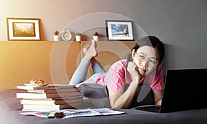 Working from home, new normal concept. woman working with laptop computer on bed from her room during self isolation, boring