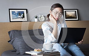 Working from home, new normal concept. woman working with laptop computer on bed from her room during self isolation with stress