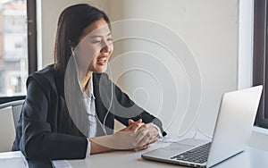 Working from home use internet communication concept. Asian young woman wear earphones talking in video conference with