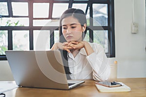 Working from home using internet communication concept. Asian young woman wear earphones talking  in video conference with