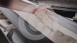 A working man checks the quality of the sand-clay mixture. Conveyor line with raw materials in production.