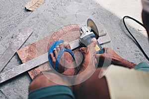 Working man cutting metal bar with circular saw.