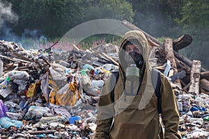 A working man in a gas mask against the backdrop of burning garbage. A lot of plastic bags thrown to the dump. From the plastic de