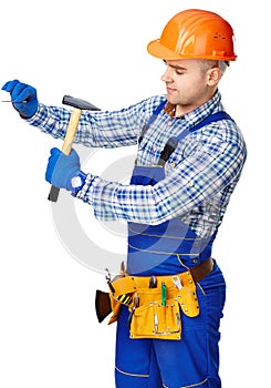 Working man with hammer driving a nail in wall