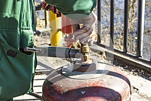 The working man has controlled gas cylinder propane closeup, the background is blurred with bokeh effect