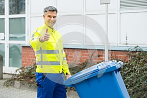 Working Man Holding Dustbin On Street photo