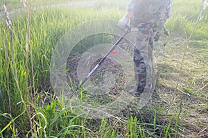 Working man mow high green grass with electric lawn mower