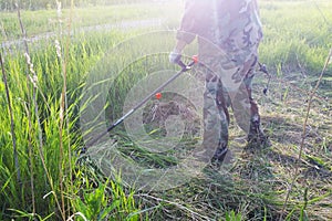 Working man mow high green grass with electric lawn mower