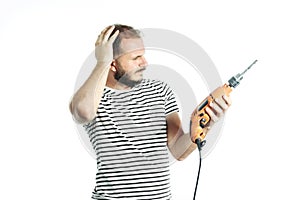 A working man in perplexity pondered look at a power tool - electric drill. Isolated on white photo