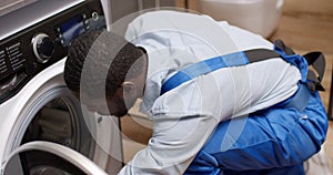 Working man plumber repairs washing machine in home. Washing machine installation